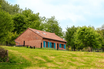 Maison flamande typique avec briques rouges, au milieu des champs