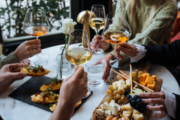 Friends having a dinner party with different kinds of appetizers and wine.