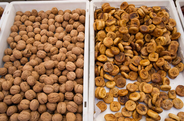 Fresh walnuts and dried bananas displayed in white trays at a local market showcasing natural food...