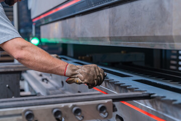Machine de découpe laser en fonctionnement dans un atelier, réalisant des pièces industrielles métalliques avec précision.