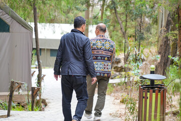 Two men walk around a luxury camping resort in the wild. Glamorous camping amidst the lush greenery...