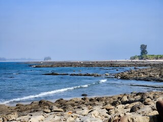 Rocky coastline with ocean waves and distant tower
