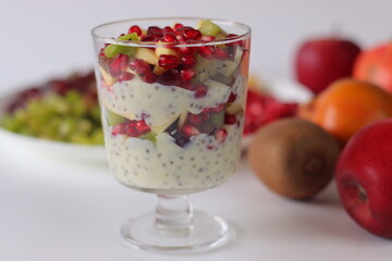 Chia seed pudding or chia custard in glass cups topped with pomegranate, kiwi, apple, and grapes