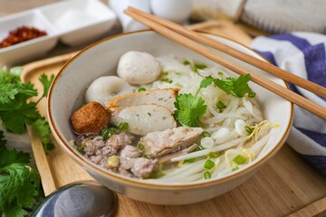 Clear pork noodle soup with thin rice noodles in ceramic bowl with chopsticks