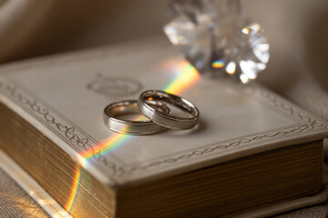 Gay Marriage Concept with Rings and Rainbow Light on Scripture Book