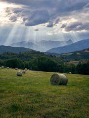 Campo en la montaña con rayos de sol y paquetes de paja