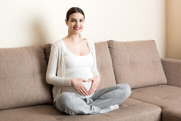 Young pregnant woman holds wooden heart. Love concept