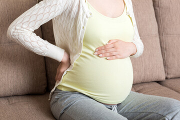 Pregnant woman with painful belly on sofa at home