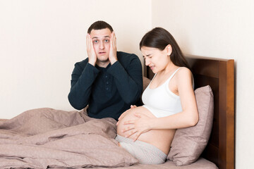 husband shocked while his pregnant wife has contractions on bed in home
