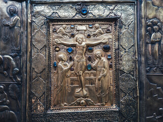 Ancient Orthodox icon of Crucifixion with carved golden relief and gemstones, symbolizing Christian faith, church heritage and religious art. Byzantine culture, sacred history and spirituality.