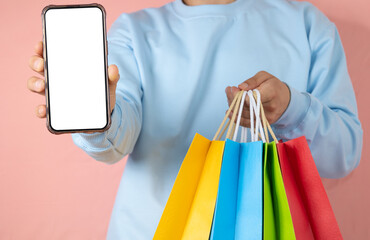 Unrecognizable man showing his cell phone with blank screen while holding multi colored shopping...