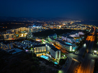 Stunning aerial sunset to night transition over Turkler in Alanya, Turkey. Alanya coastline,resorts,marina,hotels and city lights along the Mediterranean Sea drone view. Mediterranean Sea coastline.