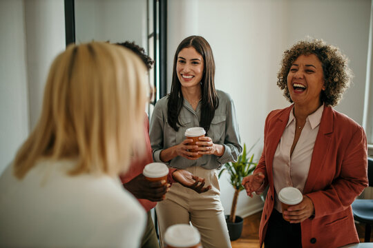 Businesswomen enjoying coffee break, laughing and talking in office