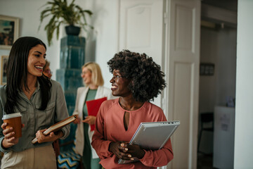 Businesswomen walking and talking in office corridor
