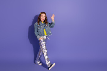Happy young student girl in trendy outfit waving hand gesture against colorful violet background