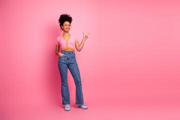 Confident young woman has fun expressing joy in stylish attire with a cheerful gesture on a pink...