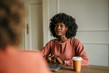 Businesswoman listening to colleague during informal meeting in office