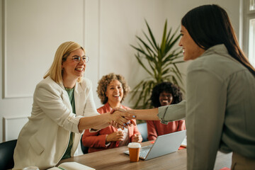 Businesswomen shaking hands after successful meeting in modern office