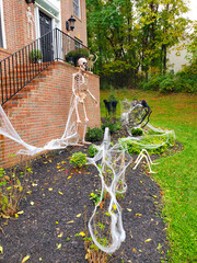 Skeletons and cobwebs on the doorstep of a house decorated for Halloween.