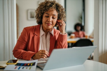 Businesswoman working on laptop and having a conference call in office
