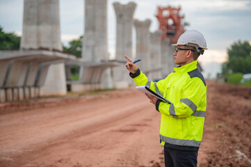 An Asian male engineer works at a motorway bridge construction site,Civil worker inspecting work on...