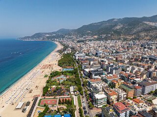 Fototapeta premium Drone view of Alanya city, Turkey. Coastline, Mediterranean Sea, harbor, historic castle on the hill, and sprawling urban area with mountains in the background on a clear summer day. Alanya, Turkey