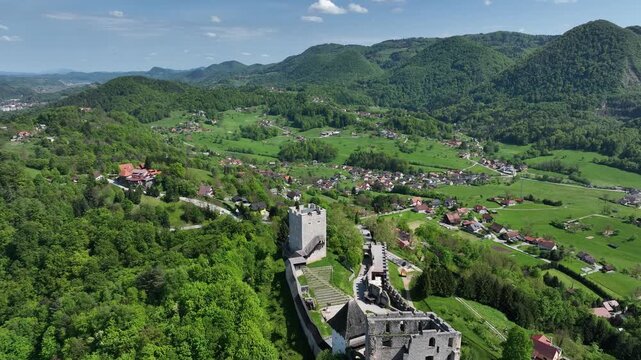 Aerial views of Slovenian landscapes in spring. Drone footage of Celje and its fortress. Historic Celje Castle overlooks vibrant spring townscape, combining medieval legacy and modern life.