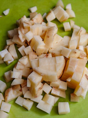 A pile of diced white potatoes on a vibrant green cutting board, ready for cooking