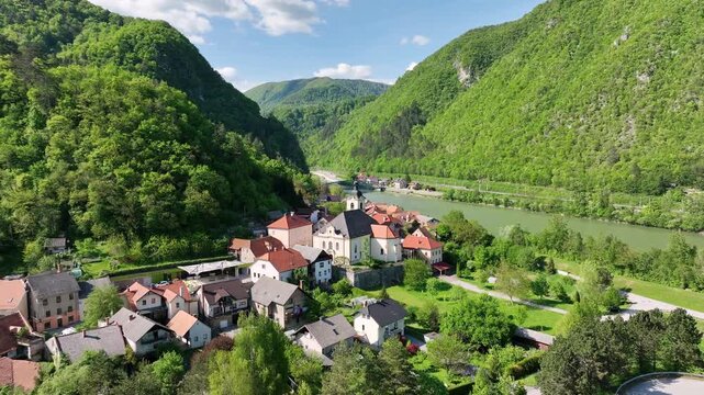Aerial views of Slovenian landscapes in spring. Small Slovenian town Radece by river Savinja. Surrounded by green hills and forests, shown from the air in warm May sunlight.