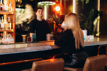 Woman Sitting at a Bar Counter Enjoying a Drink in a Modern Setting