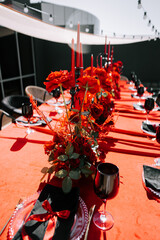 Elegant red-themed dinner setting with flowers and candles at an outdoor location