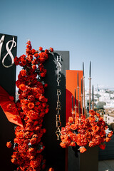 Elegant birthday celebration with red floral decorations in a rooftop setting during daylight