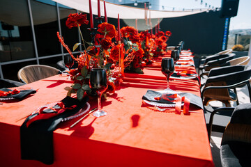 Elegant red-themed table setting at an outdoor event during a sunny afternoon