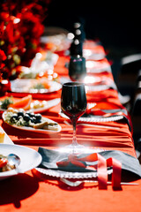 Elegant dining setup with red decorations and gourmet dishes in a sunny outdoor setting