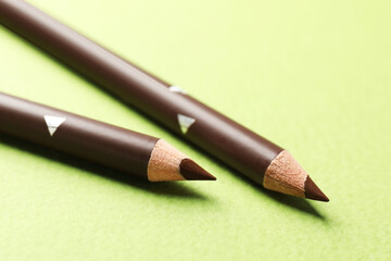 Brown eyebrow pencils on green background, closeup