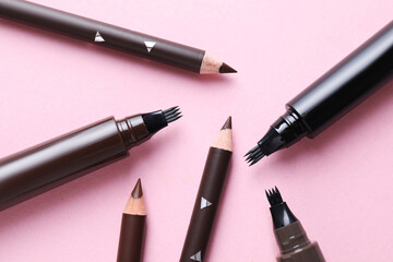 Different eyebrow pencils on pink background, flat lay
