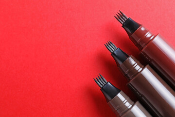 Liquid eyebrow pencils on red background, above view. Space for text
