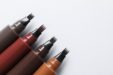 Liquid eyebrow pencils on white background, flat lay. Space for text