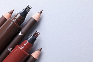 Different eyebrow pencils on white background, above view. Space for text