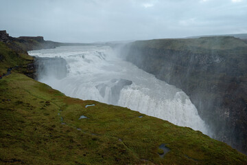 Dynamic Gullfoss waterfall in Iceland crashing into a canyon in cloudy weather. Concept of raw natural energy, adventure, geology, and scenic Nordic travel experience.