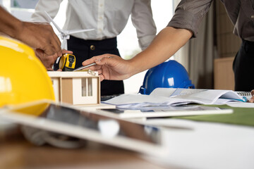Sustainability in Action. Team measuring eco-friendly building model for innovative design.