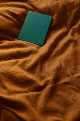 Green blank book on orange textured cloth background