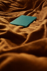 Green blank book on orange textured cloth background