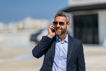 Rich businessman in suit. Business portrait. Successful businessman walking with laptop in parking....