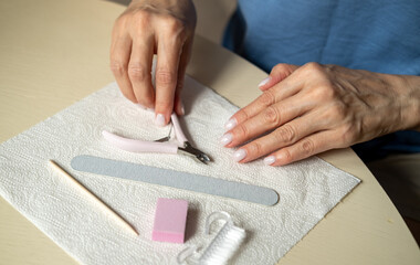 Nail care at home, close-up manicure. Using cuticle nippers, a nail file, a sanding pad, a brush and an orange stick. 