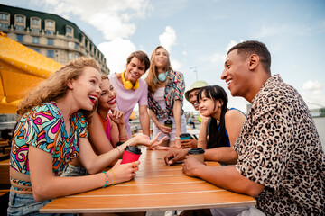 Group of cheerful friends enjoying outdoor gathering at a colorful urban café during a sunny day