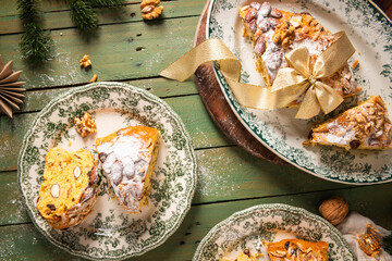 Portuguese Bolo Rainha slice: sugared nuts on festive bread, on a green table with Christmas ornaments. A traditional dessert for Christmas, New Year's & Epiphany. Top view