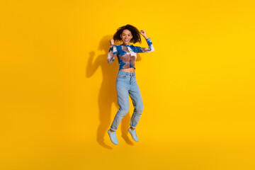 Cheerful young woman jumping with joy wearing a colorful printed shirt and jeans on a vibrant...