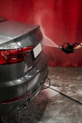 Pressure Rinsing Car After Foam Application. Detailed cleaning using pressure hose ensures no foam...