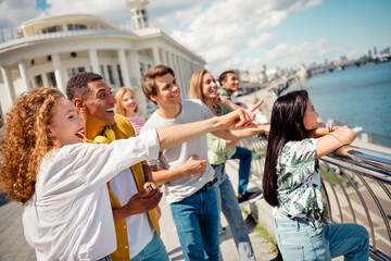Group of diverse young friends enjoying a summer day together by the water in a lively urban setting